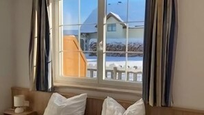 Ein Hotelzimmer mit großem Fenster, einem Bett mit weißer Bettwäsche und einem hölzernen Kopfteil.
