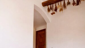 Una escalera que lleva a una puerta, un jarrón grande y frascos en un estante.