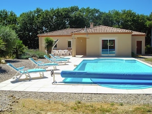 A swimming pool with lounge chairs, a covered patio, and a building with a tiled roof. - Panoramic Poolside Villa (La Croix-Blanche)