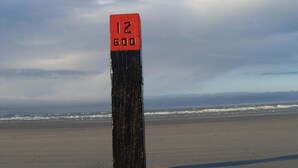 Une plage avec un grand poteau noir sur lequel est inscrit en rouge le chiffre « 12 600 ».