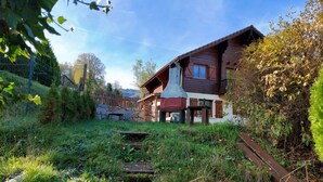 A rustic wooden house with a sloped roof, a chimney, and a small porch area. - Apartment in the Vosges (Saint-Maurice-sur-Moselle)