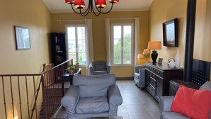 A living room with a grey sofa, a coffee table with a plant, a staircase with a railing, and a television on the wall. - Montbrun Vineyard Escape (Montbrun-des-Corbières)
