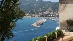 A coastal town with a marina, boats, and a mountainous backdrop.