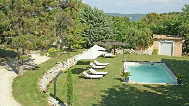 A pool area with a stone wall, lounge chairs, and a small building with a door. - Villa in Reillanne With Private Pool (Reillanne)