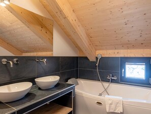 Une salle de bain moderne avec deux lavabos, une baignoire et une douche.