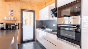 A modern kitchen with stainless steel appliances, wooden walls, and a large window. - Modern Chalet With Sauna (Sankt Georgen am Kreischberg)