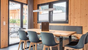 A modern interior with a wooden table and chairs, large windows, and a view of the outdoors. - Modern Chalet With Sauna (Sankt Georgen am Kreischberg)