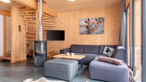 A modern living room with a wooden interior, a fireplace, a sofa, and a large window. - Modern Chalet With Sauna (Sankt Georgen am Kreischberg)