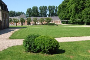 A courtyard with a lawn, a hedge, and a building with a brick facade. - House Near Merlimont-plage and Historic Abbey (Gouy-Saint-Andre)