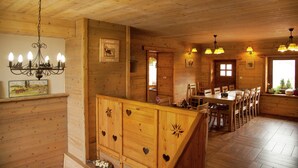 Een houten interieur met een eetgedeelte, een houten plafond en wandlampen.