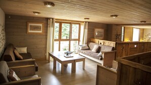 Een houten interieur met een bank, een tafel en een raam met gordijnen.