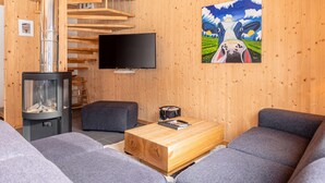 Ein gemütliches Wohnzimmer mit Kamin, einem Flachbildfernseher und einem Bild an der Wand.