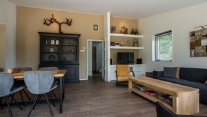 A modern living room with a dining area, a sofa, and a TV. - Villa Near Veerse Meer With Garden Views (Kamperland)