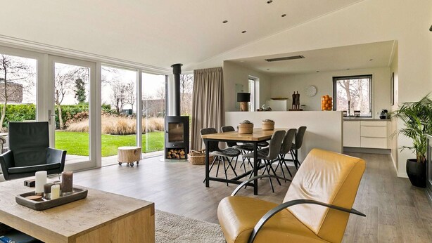 A modern living room with a fireplace, dining area, and kitchen. - Villa Near Veerse Meer With Garden Views (Kamperland)
