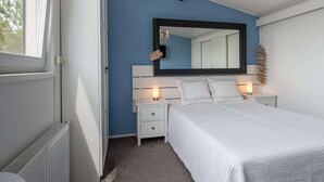 A bedroom with a bed, bedside tables, a mirror, and a radiator. - Villa Near Veerse Meer With Garden Views (Kamperland)