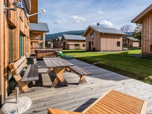 A wooden cabin-style building with a deck, outdoor seating, and a grassy yard. - Spacious Chalet With hot tub (Sankt Georgen am Kreischberg)