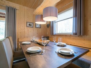 A wooden dining table set with plates, glasses, and cutlery, with a basket of breadsticks and a candle centerpiece. - Spacious Chalet With hot tub (Sankt Georgen am Kreischberg)