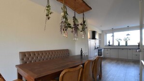 Une cuisine moderne avec une table à manger en bois, des chaises en osier et des plantes suspendues.
