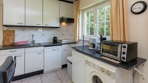 A compact kitchen with white cabinets, a washing machine, a microwave, and a coffee maker.