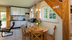 A kitchen with white cabinets, a wooden dining table with chairs, a coffee machine, and a sign indicating no smoking.