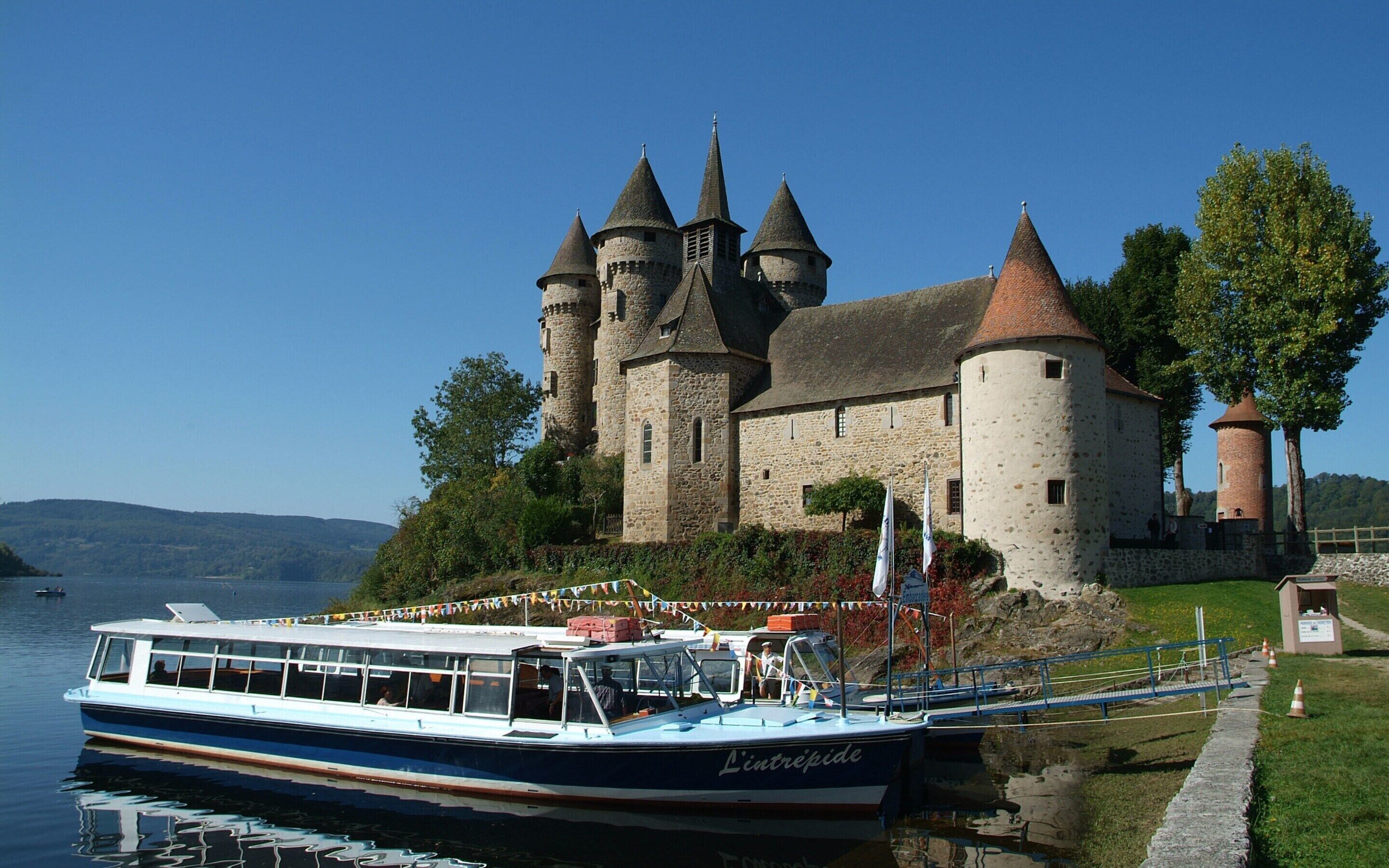 A castle with multiple towers, a boat docked in front, and a clear sky.