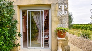 Un bâtiment en pierre doté d’une porte coulissante en verre, d’une plante en pot et d’un portail en métal.