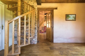 A wooden spiral staircase leading to a room with a stone wall and a framed picture on the wall. - Cottage in Chaleix Near Forest & Lake (Chalais)