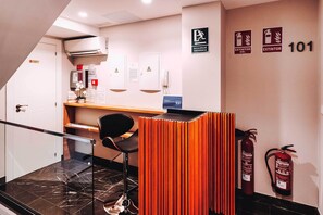 A hotel reception area with a desk, chairs, a fire extinguisher, emergency exit signs, and a staircase. - GBH Hotel-Apartamentos Posidonia (Benidorm)