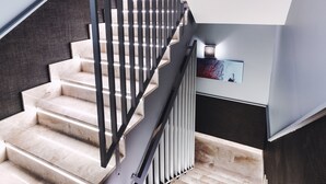Una escalera moderna con barandilla negra y un cuadro en la pared.