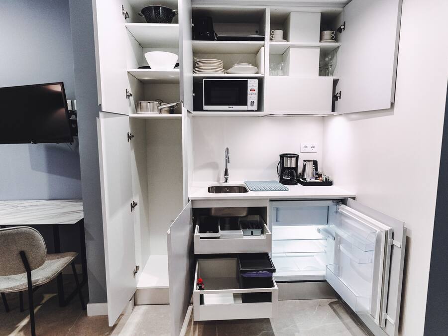 Una kitchenette compacta con microondas, pileta y cajones para guardar.