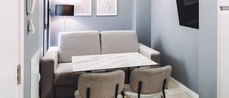 A modern room with a sofa, two chairs, a marble table, and artwork on the wall.