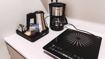 Una cafetera, un hervidor y una balanza digital sobre una encimera blanca.