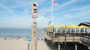 A beachside pier with a Texel flag, wooden deck, and yellow umbrellas. - Apartment in a Quiet, Rural Area, not far From the Centre (Callantsoog)