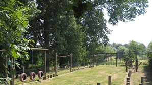 Ein Spielplatz mit Reifen-Schaukeln, einer Seilbrücke und einer hölzernen Kletterkonstruktion.