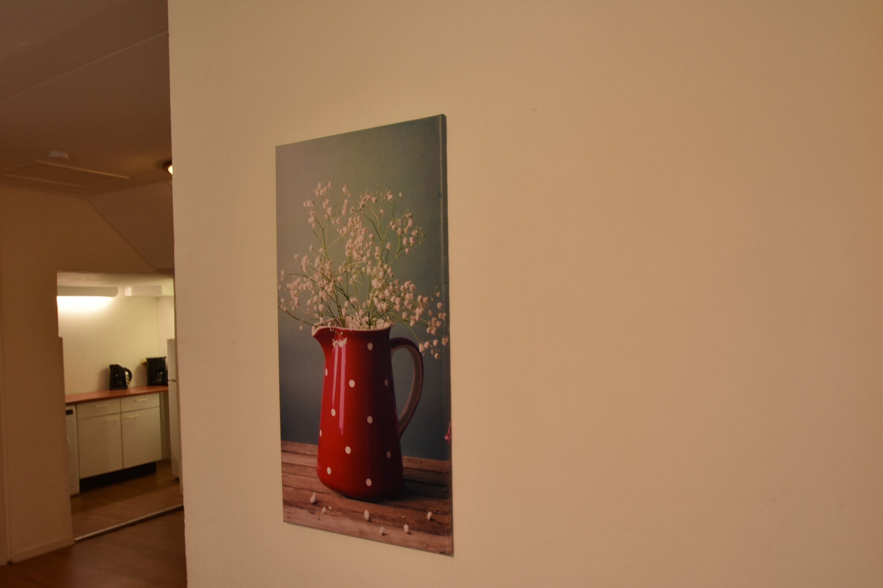 Una pintura de una jarrón rojo con flores sobre una superficie de madera.