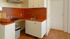 A compact kitchen with white cabinets, a stainless steel sink, and a gas stove. - Timeless Charm and Cozy Stay (Bergen aan Zee)
