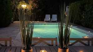 Ein Poolbereich mit zwei Liegestühlen, einer Holzterrasse und Kübelpflanzen.