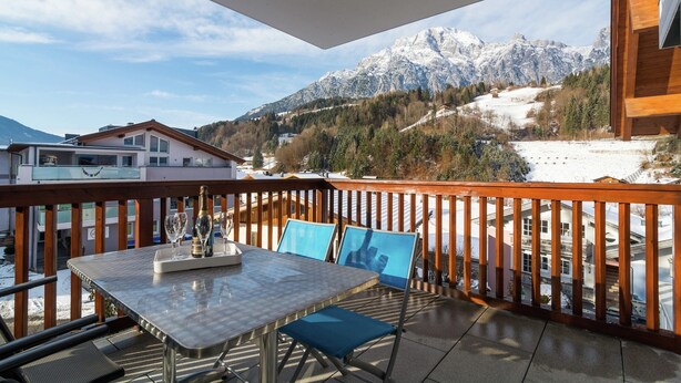 Ein Balkon mit Tisch, Stühlen und einer Flasche.