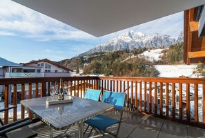 En balkon med et bord, stole og en flaske.