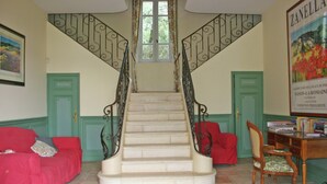 A staircase with ornate metal railings, a green door, a red sofa, and a wooden chair. - Holiday Home Near Mont Ventoux Pool (Vaison-la-Romaine)