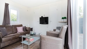 A modern living room with a sofa, armchair, and glass coffee table. - Chalet in Holiday Park With Private Terrace (Baarle-Nassau)