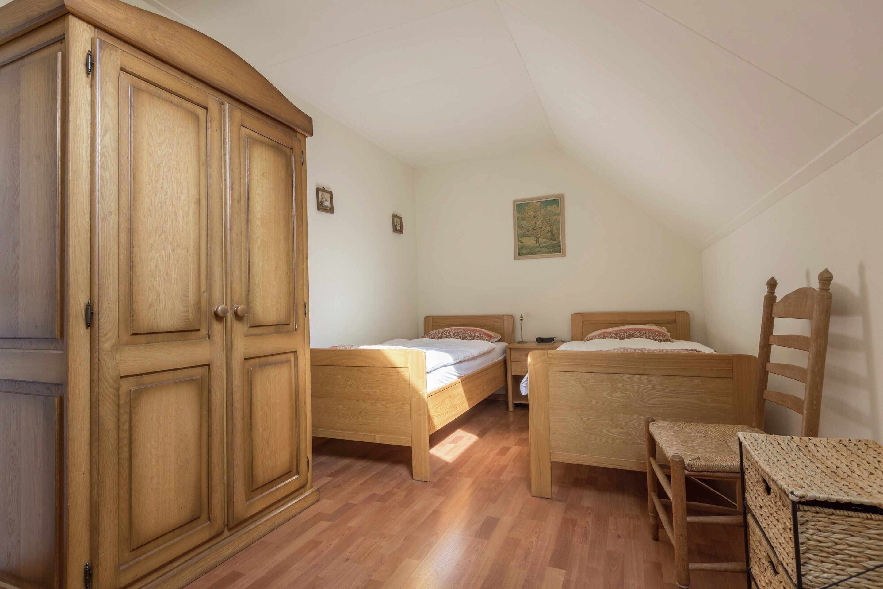 Un dormitorio con dos camas de madera, un armario de madera y una mesita pequeña.