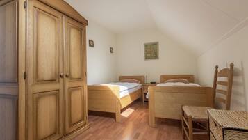 Un dormitorio con dos camas de madera, un armario de madera y una mesita pequeña.