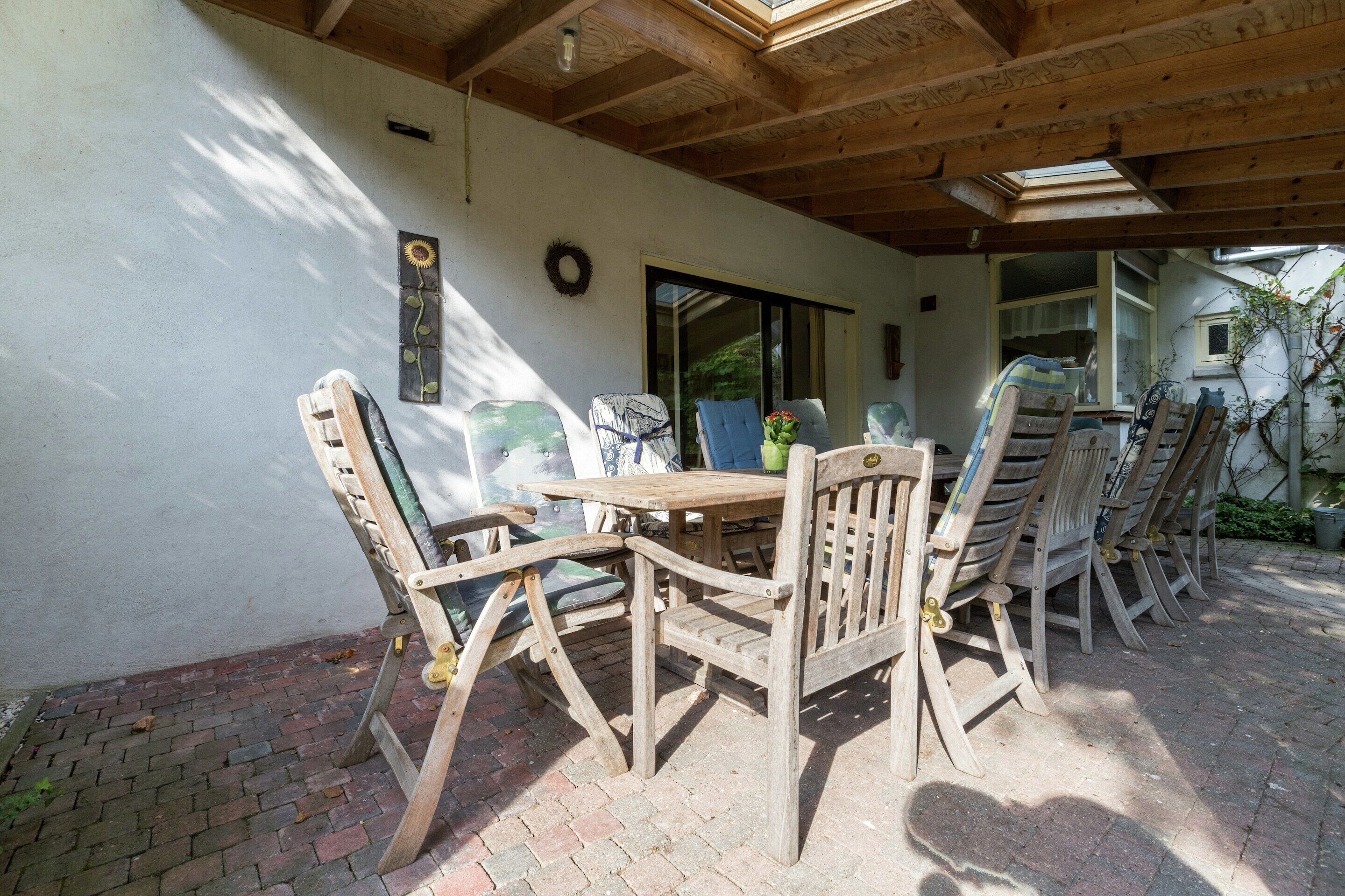 Eine Terrasse im Freien mit Holzmöbeln, einem Backsteinboden und einer Holzbalkenkonstruktion.