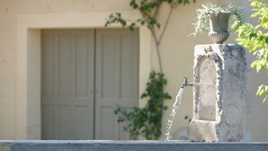 A water fountain with a plant on top, a door in the background, and a tree to the right. - Mansion in Provence With Pool & Near Town (Valreas)