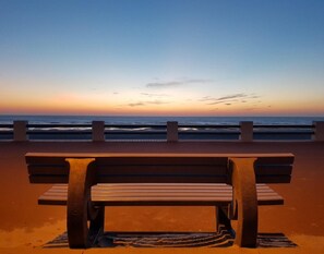 Een bankje aan het strand met uitzicht op de oceaan bij zonsondergang.
