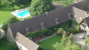 Een groot gebouw met verschillende dakdelen, een zwembad en een auto ervoor geparkeerd.