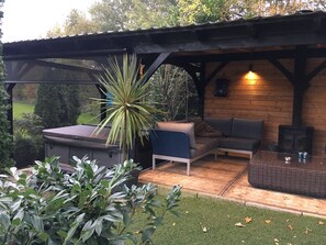 A covered outdoor seating area with a sofa, a table, and a hot tub. - Alluring Holiday Home in Reutum-Weerselo with Hot Tub (Reutum)