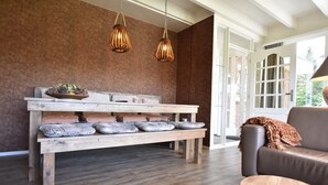 A wooden bench with cushions, a brown wall, and a brown leather sofa. - Alluring Holiday Home in Reutum-Weerselo with Hot Tub (Reutum)