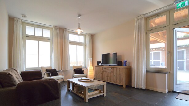 Una sala de estar con sofá, sillones, mesa de centro, televisor y mueble.